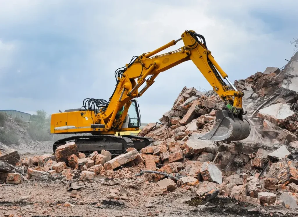 Yellow excavator clearing rubble.